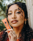 Woman holding Nopalera Flor de Madera cactus hand cream in a natural setting