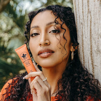 Woman holding a tube of Nopalera Flor de Madera hand cream in a natural setting