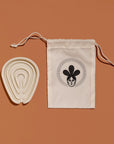 Silicone soap tray beside a Nopalera drawstring storage pouch on a warm tan background.