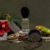 Perfume bottle labeled 'Bosque Móstico' by Nopalera surrounded by natural elements on a dark background
