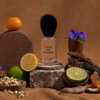 Nopalera Flor de Madera Luxury Mexican perfume bottle surrounded by citrus fruits, flowers, and wood elements representing the fragrance notes
