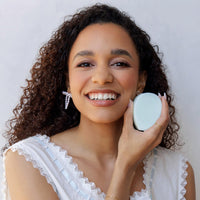 Woman holding a small round mirror with a white background
