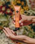 Hand applying Flor de Madera cactus hand cream with a floral background
