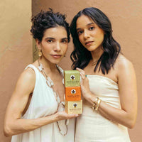 Two women holding Nopalesa boxes against a beige background