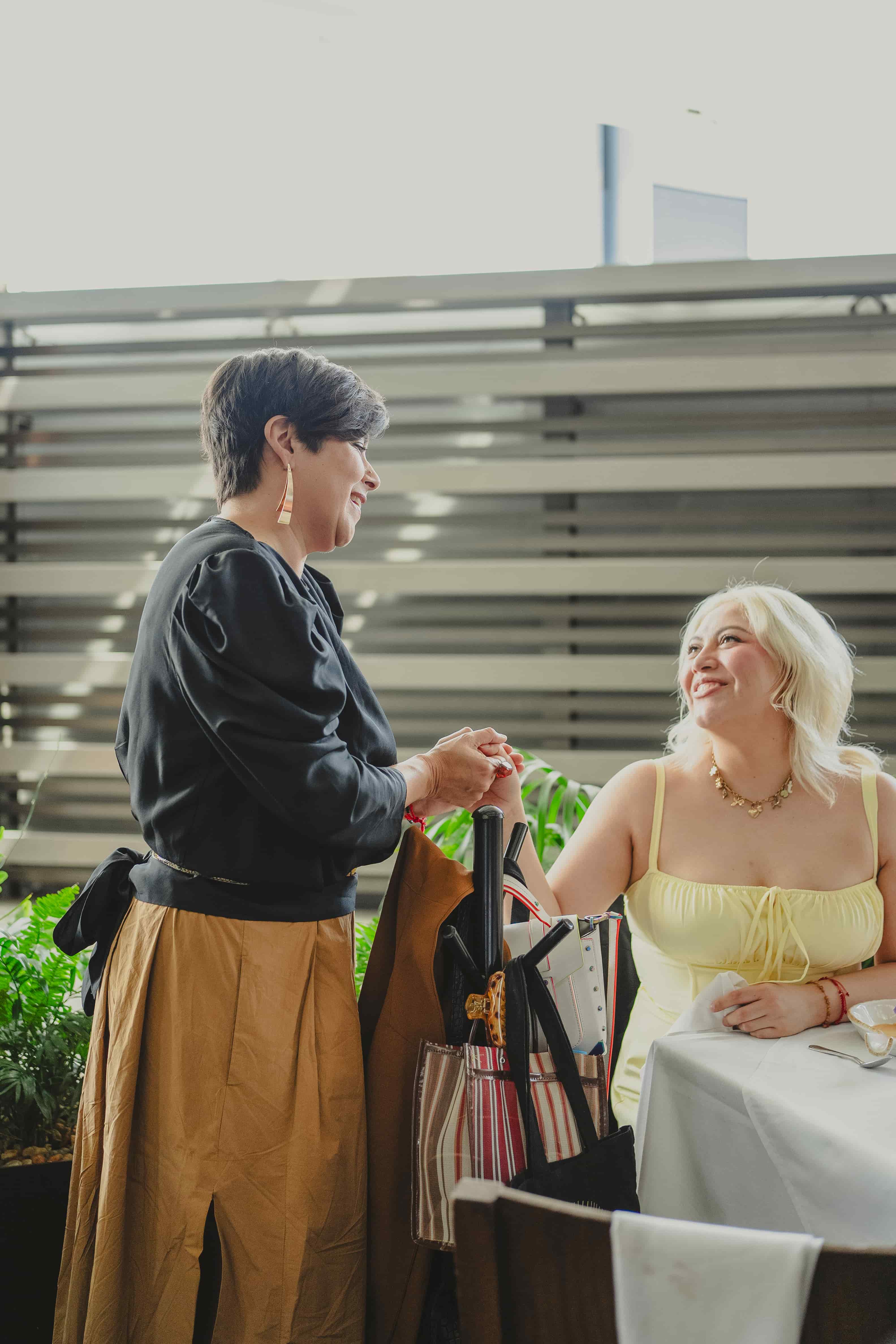 Sandra Velasquez interacting at an outdoor dining table with a modern building in the background.