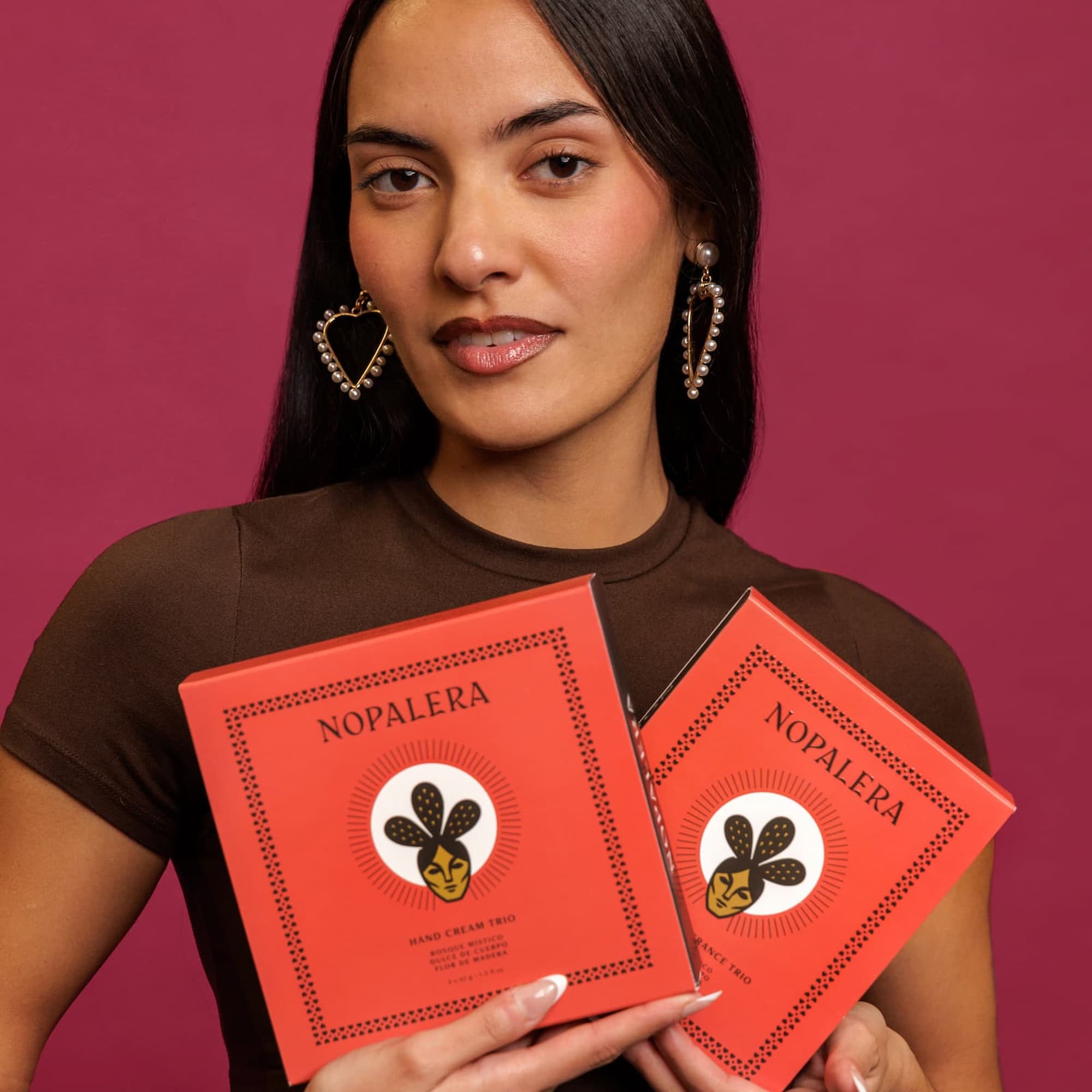 Woman holding two red 'Nopalera' packages against a pink background