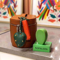 Nopalera cactus soap with green soap dish and leather keychain accessories displayed next to a brown leather travel case on a countertop.
