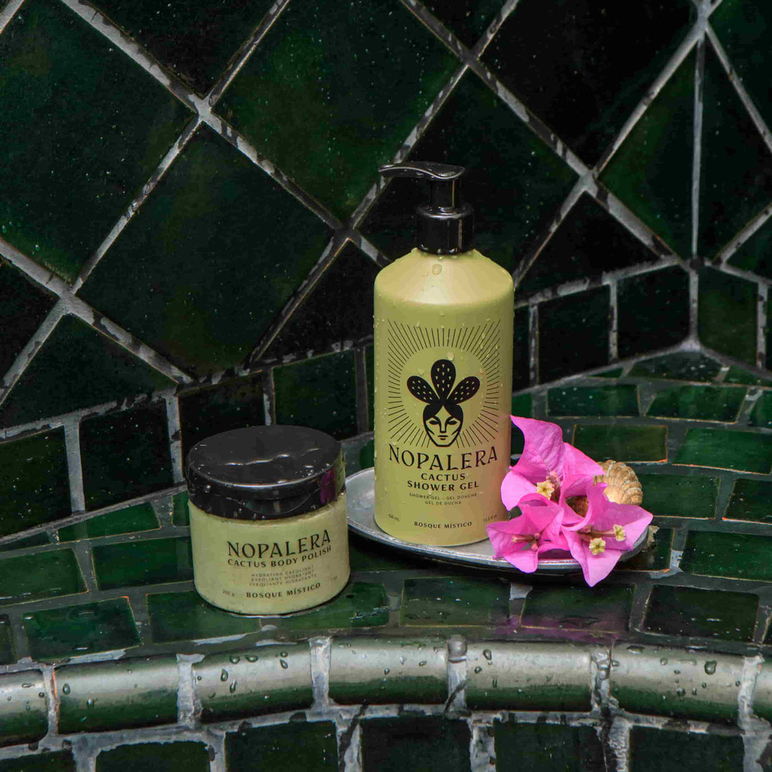 Nopalera body products on a green tiled bathroom shelf with pink flowers.