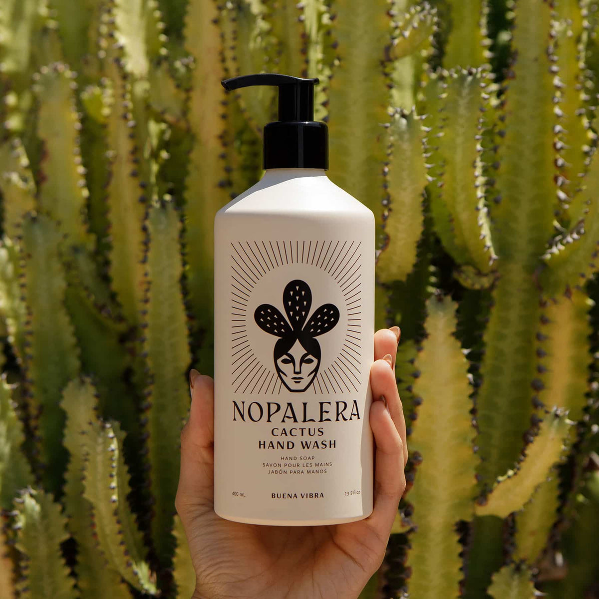 Nopalera Buena Vibra Cactus Hand Wash held in front of a cactus.