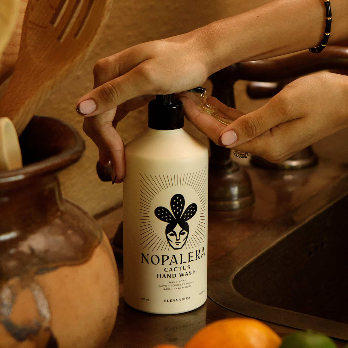 Hands dispensing Nopalera Buena Vibra Cactus Hand Wash in a rustic kitchen.