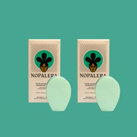 Two Nopalera solid shampoo bars on a teal background