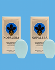 Two Nopalera solid shampoo bars with matching packaging against a blue background.