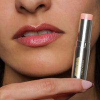 Close-up of a woman's lips with a pink lipstick and its packaging.