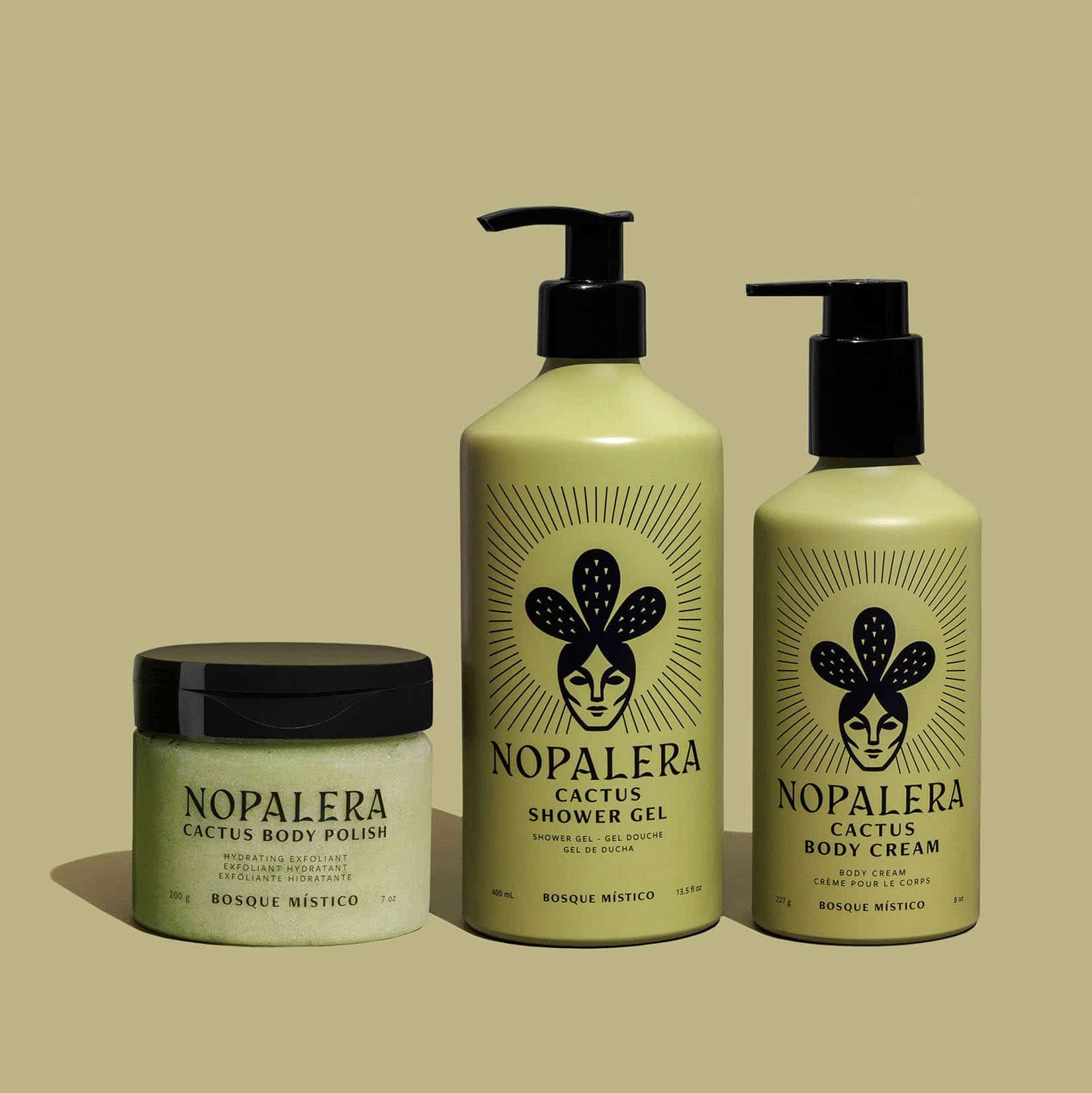 Three Nopalera Cactus Body Care products on a solid beige background: a jar of Cactus Body Polish, a pump bottle of Cactus Shower Gel, and a pump bottle of Cactus Body Cream, all in a pale green color with black lids and logos.