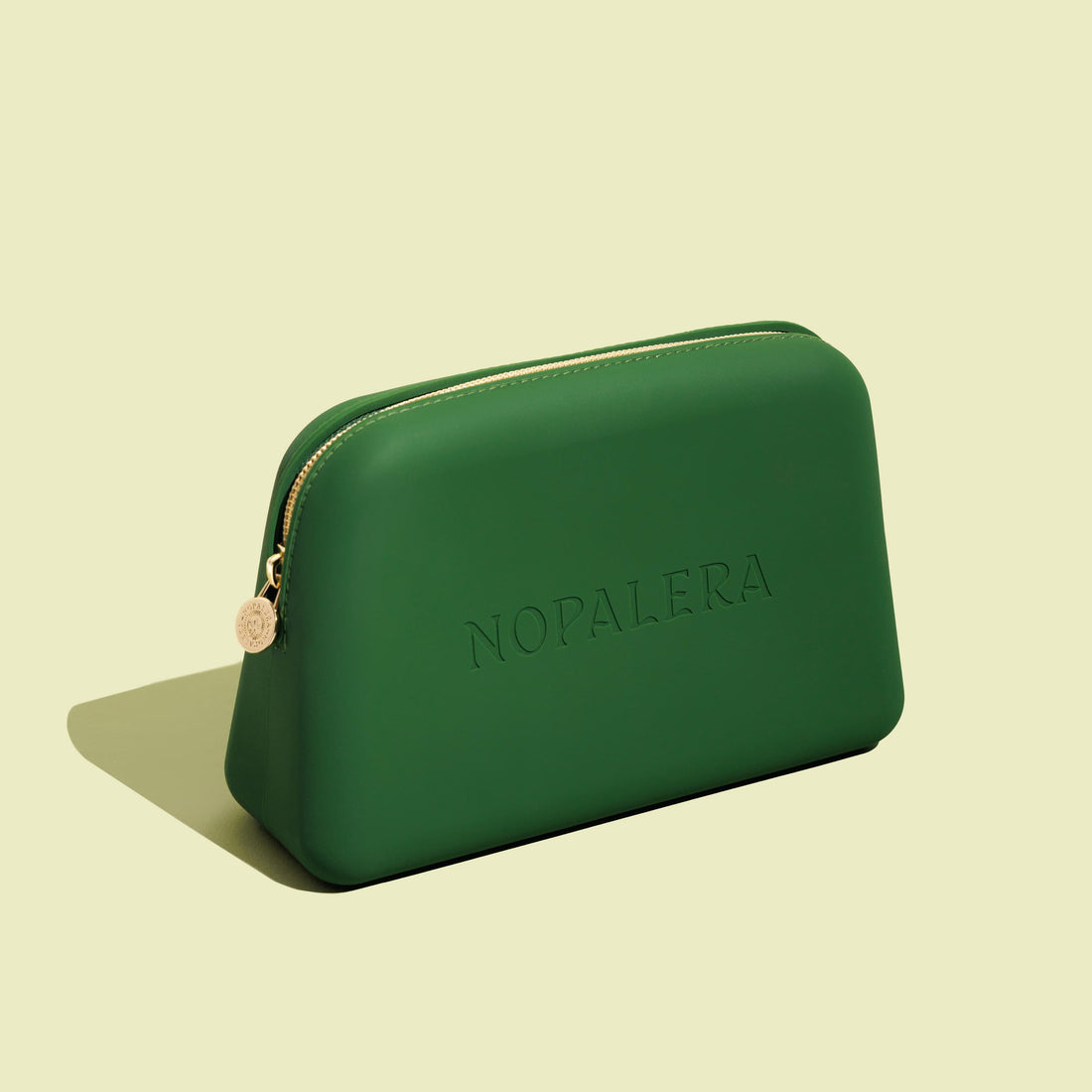 Green Nopalera cosmetic pouch with gold zipper and embossed logo on a neutral background.