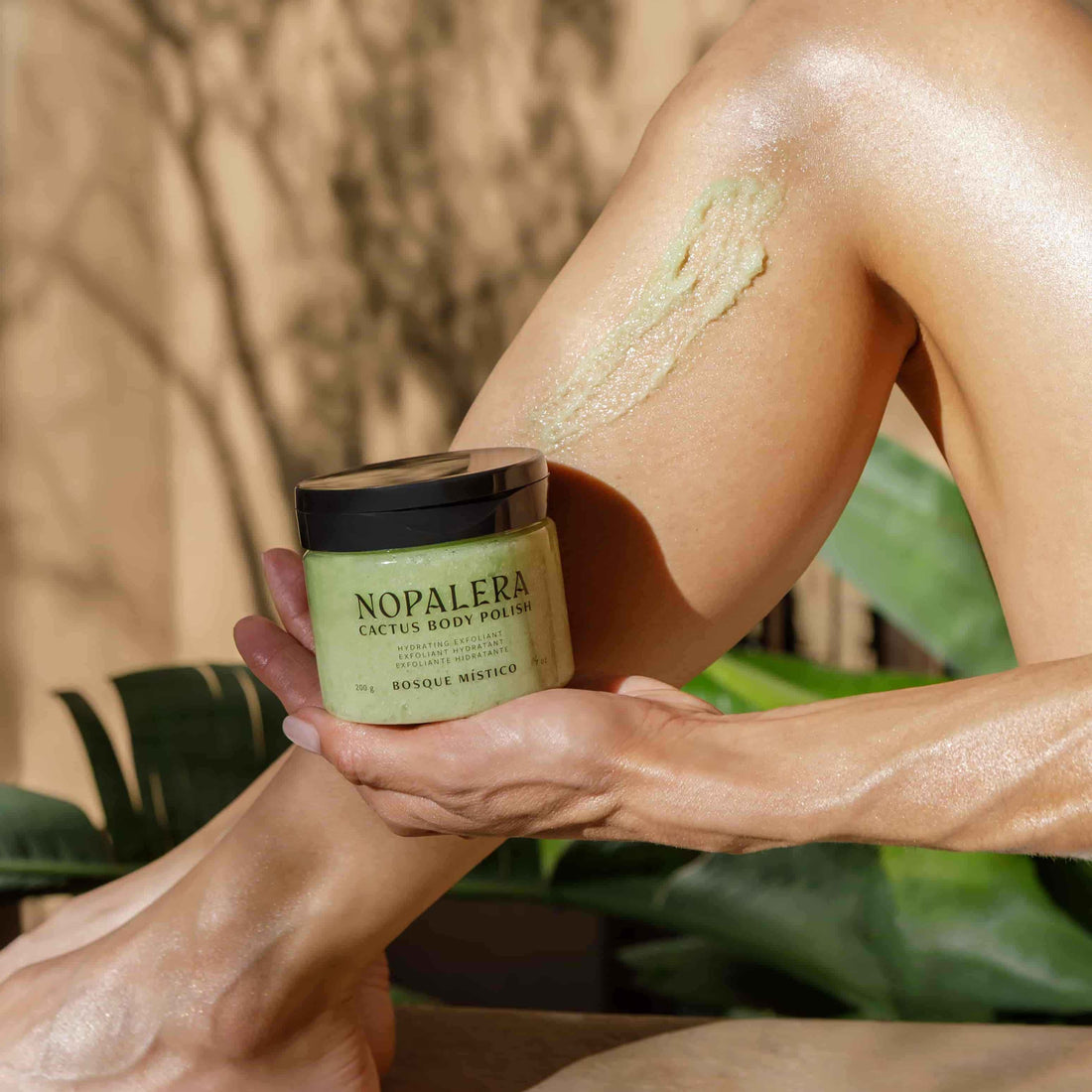 Person applying Nopalera body polish to their leg with a natural background