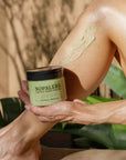 Person applying Nopalera body polish to their leg with a natural background