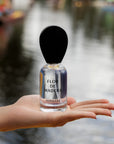 Hand holding Nopalera Luxury Mexican fragrance Flor de Madera perfume bottle with water background