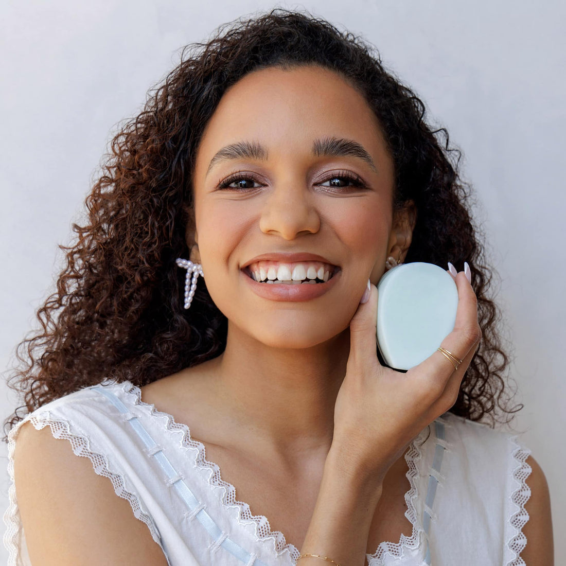 Woman holding a small round mirror with a white background