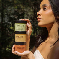 Woman holding Nopalera Flor de Madera body polish in a natural setting