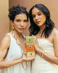 Two women holding Nopalera body polishes against a beige background