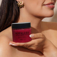 Woman holding a jar of Nopalera body polish hibiscus  against a neutral background