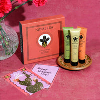 Nopalera skincare product set with three tubes and a box on a pink background and a pink card with a nopal cactus