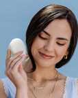 Model holding a Nopalera solid beauty bar against a soft blue background.