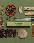 Nopalera Luxury Mexican  travel spray perfume Bosque Místico bottle surrounded by dried herbs and elements on a green background
