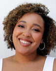 Woman with natural curly hair smiling, showing results from Nopalera shampoo and conditioner bars