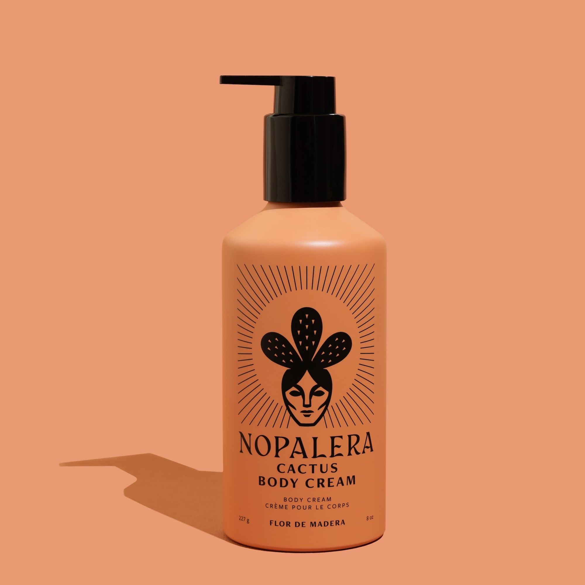 Nopalera cactus body cream bottle in Flor de Madera scent on a peach background.