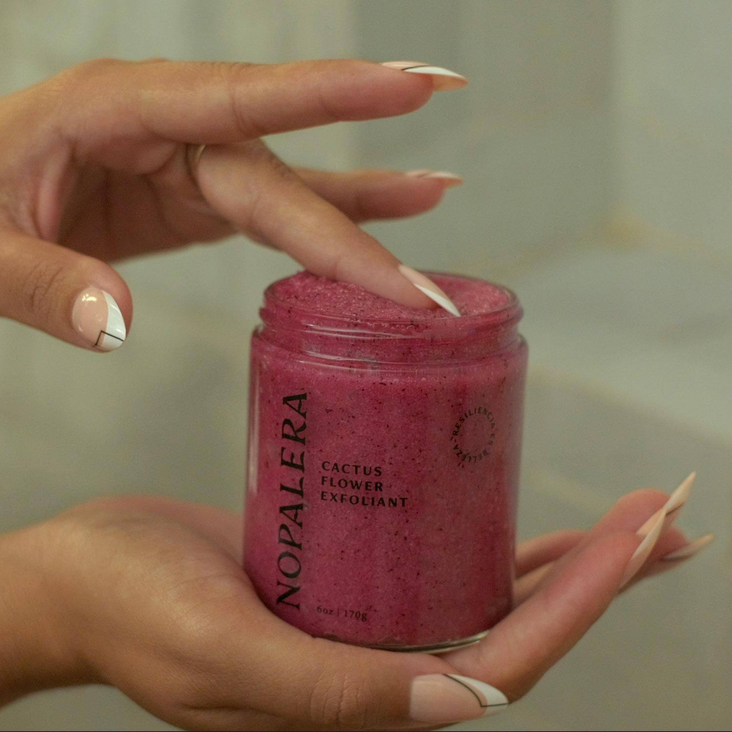 Hands opening Nopalera cactus exfoliating body scrub.