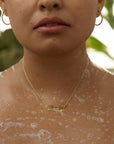 Close-up of glowing skin with soap bubbles and a gold necklace.