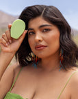 Model holding a green Nopalera beauty bar outdoors in a desert-inspired setting.