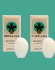 Two Nopalera solid conditioner bars with matching packaging against a green background.