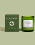 A green glass Mérida candle with a lit wick, labeled 'Nopalera' next to a matching green box with the text 'Nopalera Merida' and the Yucatan flag emblem.