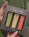 Hands dispensing Nopalera cactus hand cream in different scents with cactus plants in the background